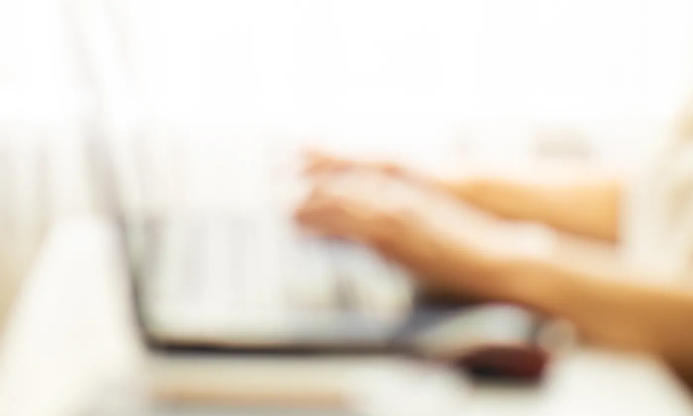 Close-up of hands typing on a laptop keyboard